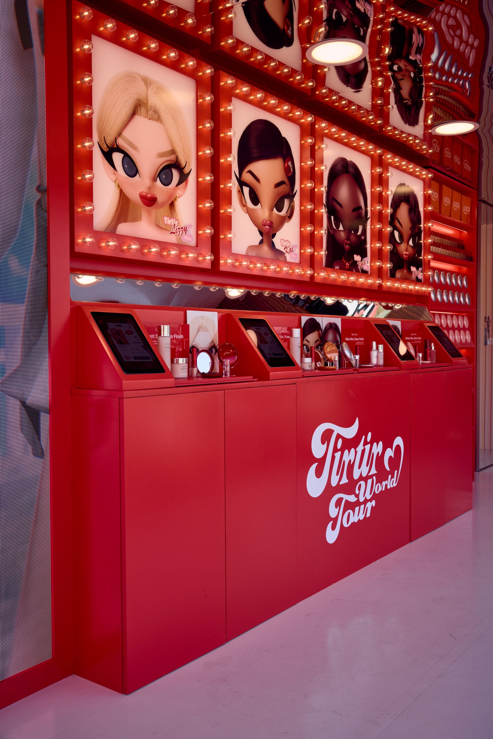 Red cosmetics counter labeled Tintir World Tour with products, screens, and cartoon portraits above.