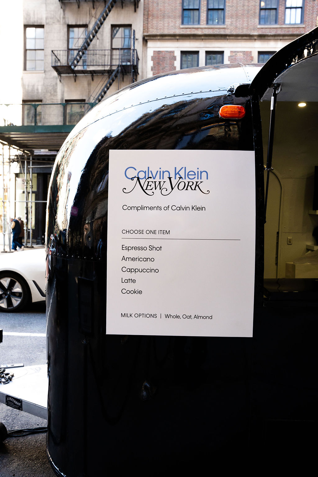 Sign on a food truck offers free drinks or cookie from Calvin Klein; milk options listed.