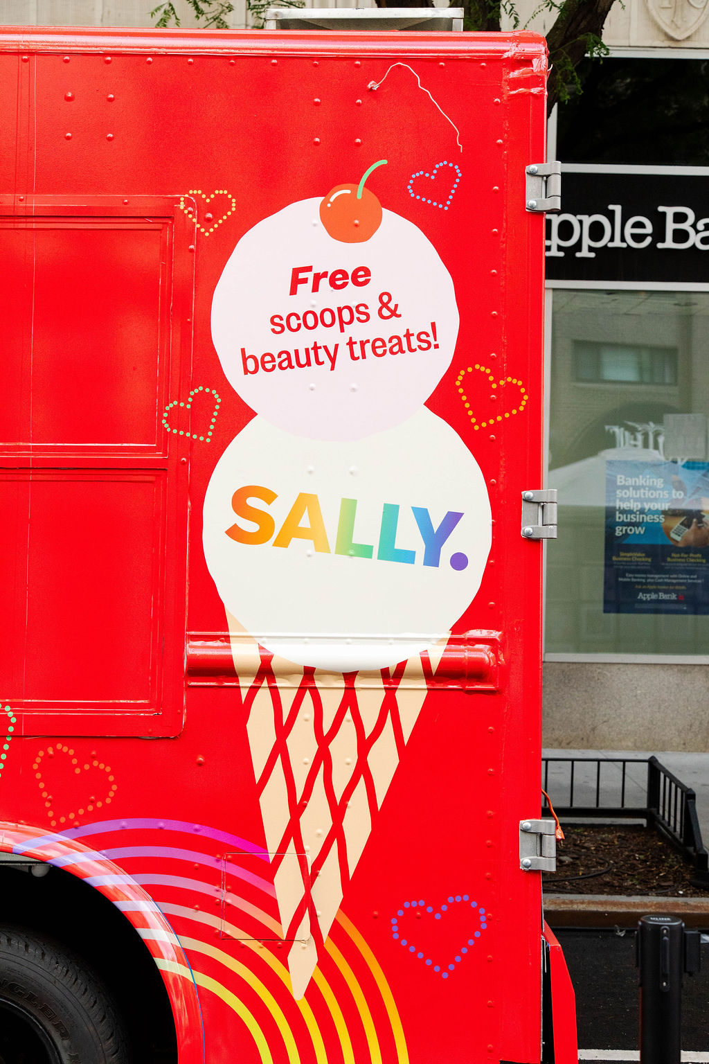 Red truck with a large ice cream cone, “Free scoops & beauty treats! SALLY.” Red hearts and rainbow.