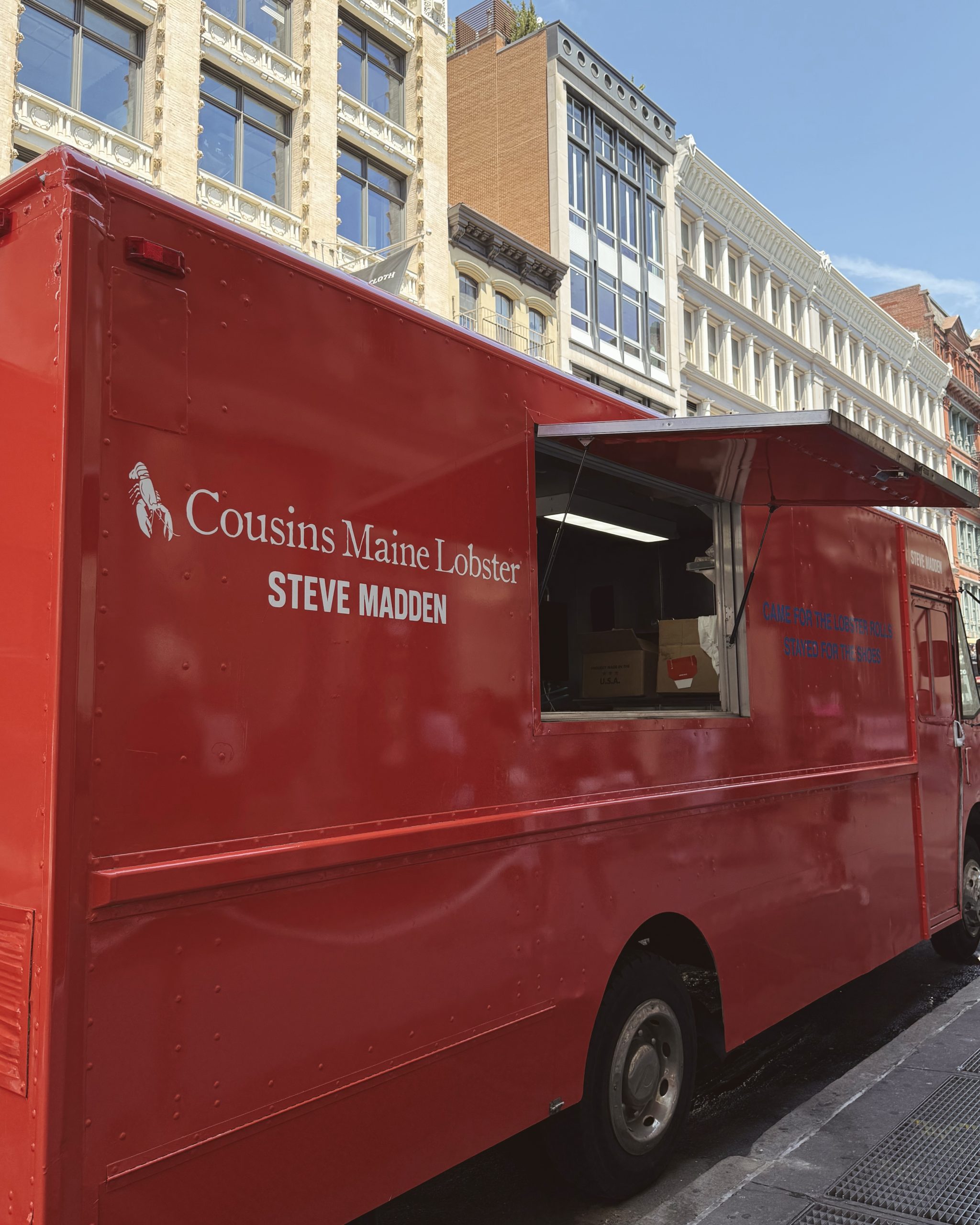 Red Cousins Maine Lobster and Steve Madden food truck with open window on city street.